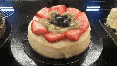 a cheesecake with strawberries kiwi and blueberries on top of it