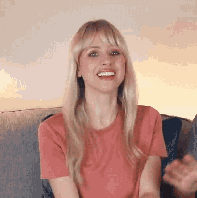 a woman is sitting on a couch and smiling .