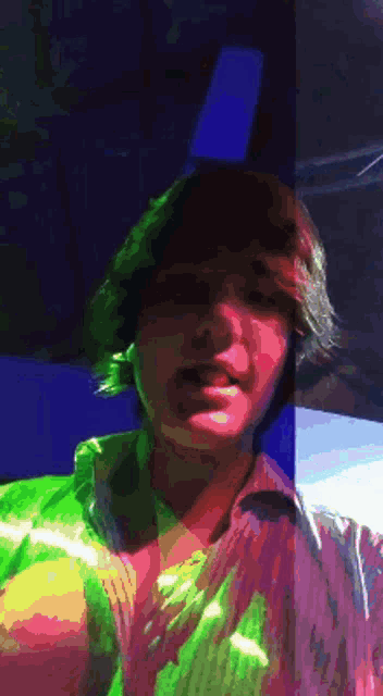a man in a green shirt stands in front of a blue background