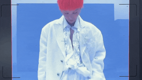 a person with red hair is standing in front of a blue wall