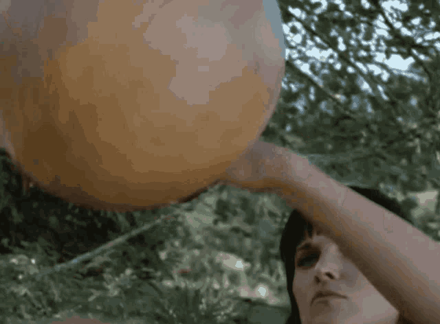 a woman is holding a large pumpkin over her head