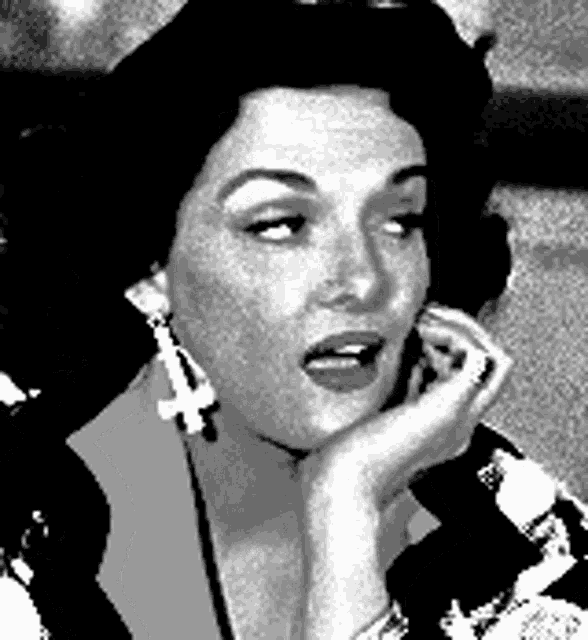 a black and white photo of a woman wearing earrings and a floral dress .