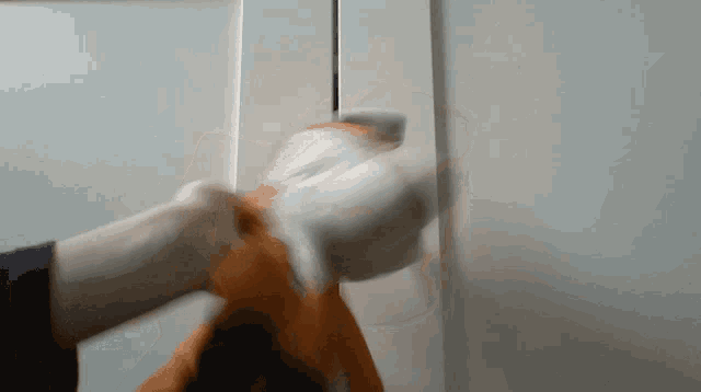 a person 's hand is holding a piece of paper in front of a white wall