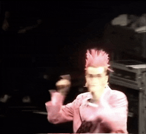 a man with a pink mohawk is dancing on stage .