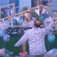 a man is standing in front of a bunch of balloons and a woman is standing behind him .