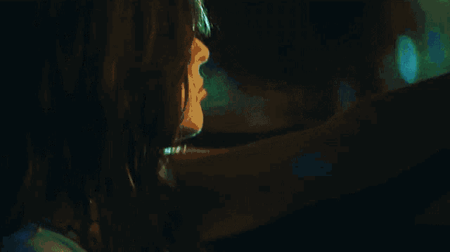 a blue light is shining on a person 's face in a dark room