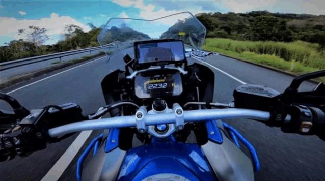 a blue motorcycle is driving down a road with the numbers 2323 on the screen