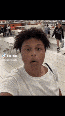 a man in a white t-shirt is taking a selfie in a mall .
