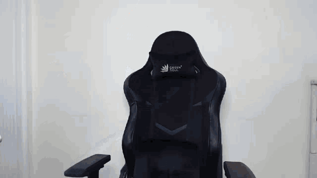 a black gaming chair is sitting in front of a white wall in a room .