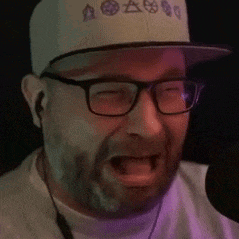 a man with a beard and glasses is singing into a microphone .