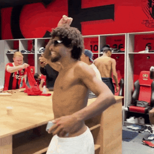 a shirtless man is standing in a locker room with a shirt that says 10 on it