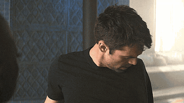 a man wearing a black shirt looks down at something