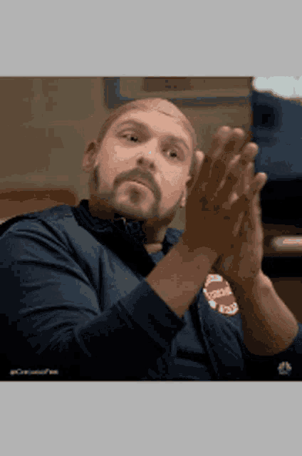 a man with a beard is clapping his hands while wearing a chicago fire department jacket