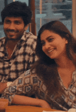a man and woman are sitting at a table and smiling