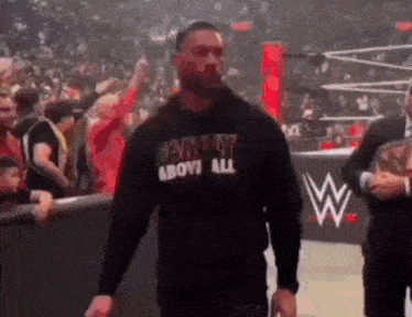 a man wearing a hoodie that says harley above all is walking in a wrestling ring .