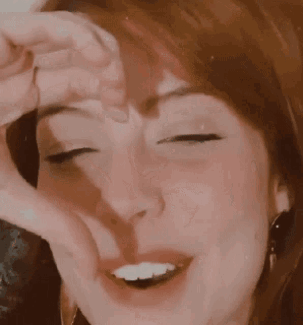 a woman is making a heart shape with her hands
