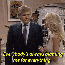 a man in a suit and tie is talking to a woman in a white dress . the woman is blaming the man for everything .