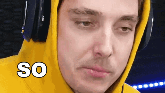 a man wearing headphones and a yellow hoodie is making a funny face and the word so is above him .
