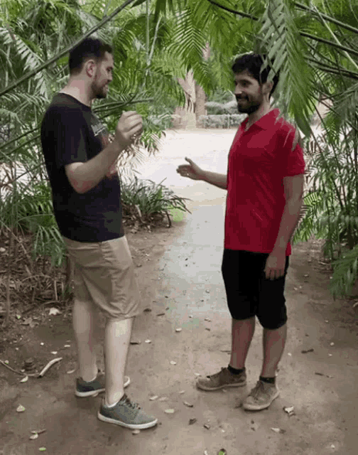 a man in a red shirt talks to another man