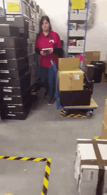 a woman in a red shirt stands in a warehouse