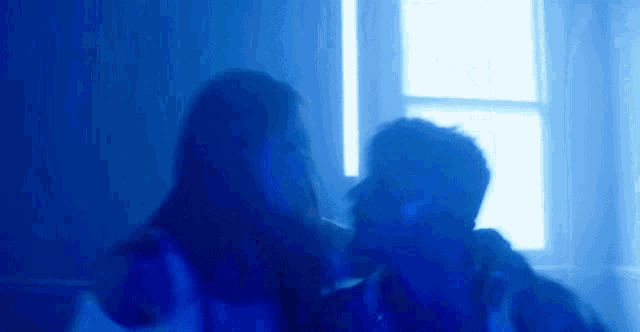 a man and a woman are standing next to each other in a room with blue lights .