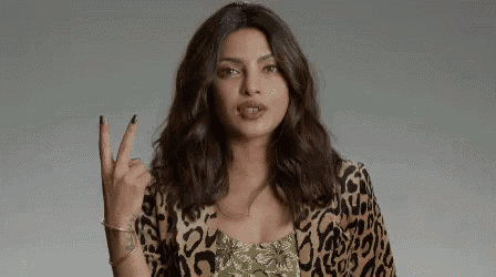 a woman in a leopard print jacket is making a peace sign with her hand .