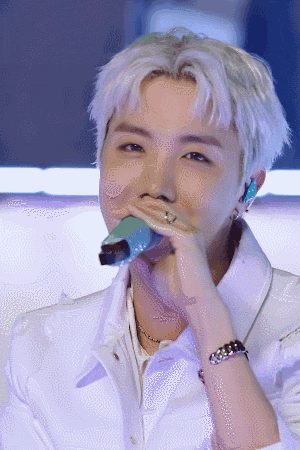 a man with white hair is holding a microphone to his mouth .