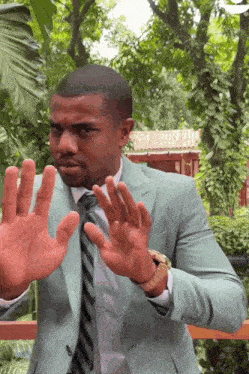 a man in a suit and tie is making a funny face with his hands