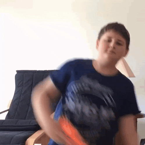 a young boy in a blue shirt is playing with a nerf gun .