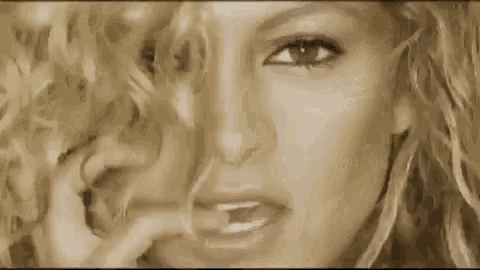 a close up of a woman 's face with her hand on her face and her eyes looking at the camera .