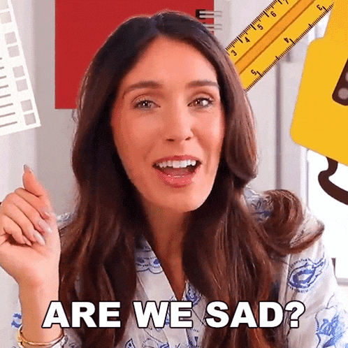 a woman is asking if she is sad with a ruler behind her