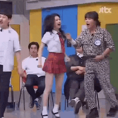 a woman in a red skirt is dancing with a man in a leopard print outfit .