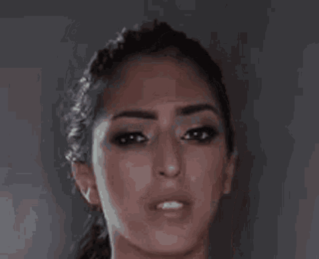a close up of a woman 's face with a ponytail making a funny face .