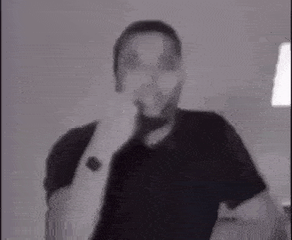 a man in a black shirt is making a funny face while wearing a watch on his wrist .