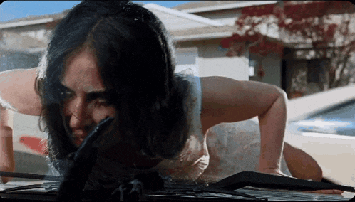 a woman with long hair is doing push ups on a car windshield
