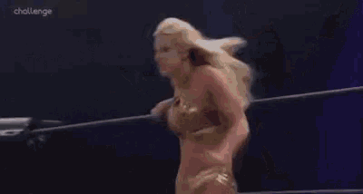 a woman is laying on the ground in a wrestling ring while a man holds her legs .
