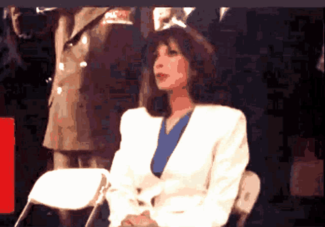 a woman in a white jacket sits in a chair