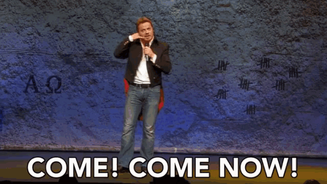 a man is holding a microphone in front of a wall and says okay cool .
