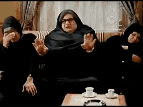 three women are sitting on a couch with their hands up .