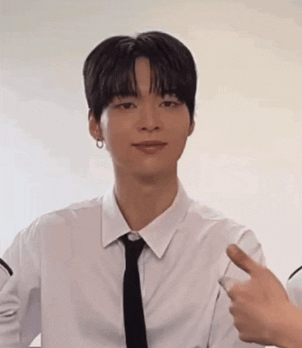 a man in a white shirt and black tie is giving a thumbs up .