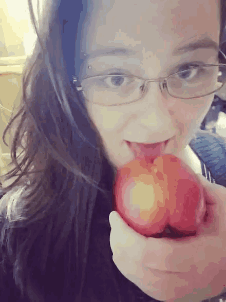 a woman with glasses is licking an apple