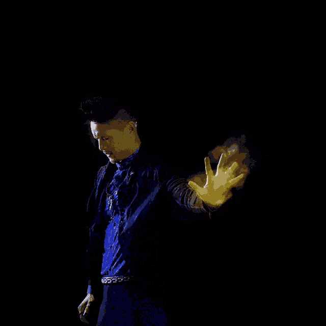 a man in a blue shirt and black jacket is holding a yellow object