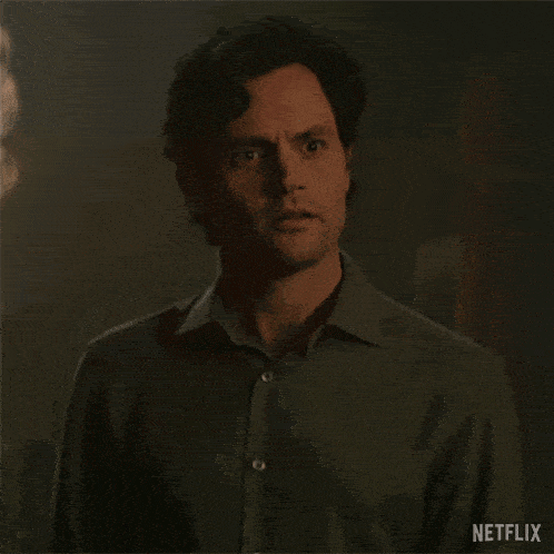 a man is standing in front of a chandelier in a dark room and looking at the camera .