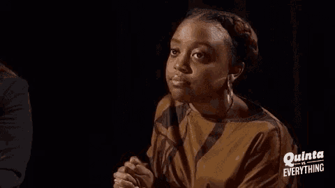 a woman in a brown shirt is clapping her hands in the dark .