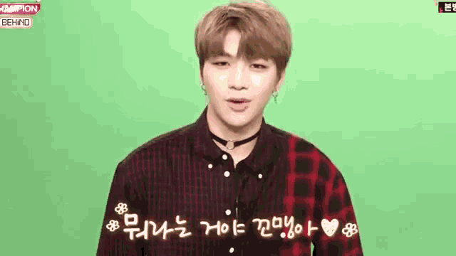 a young man wearing a choker and a plaid shirt is standing in front of a green background .