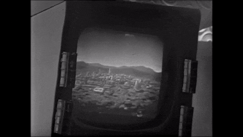 a black and white photo of a city with mountains behind it