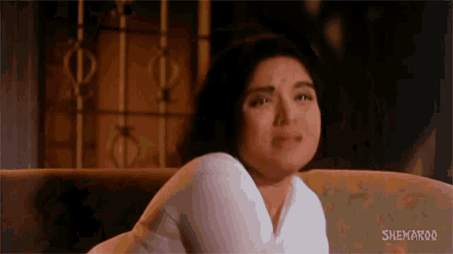 a woman is crying while sitting on a couch in a movie .