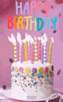 a birthday cake with candles and sprinkles is on a plate on a table .