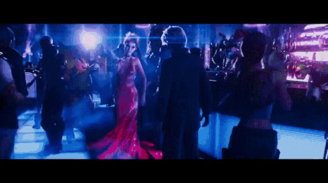 a woman in a red dress stands in front of a crowd of people