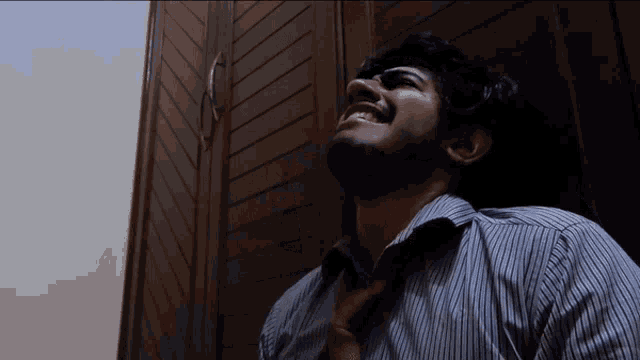 a man in a striped shirt and tie looks up at the sky